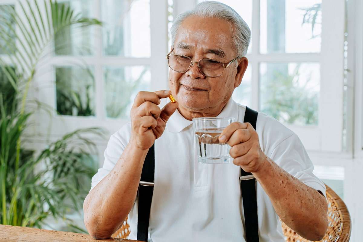 Elderly man taking vitamins.
