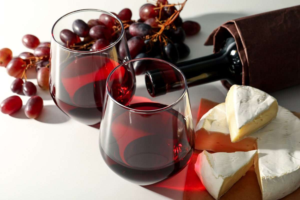 image of red wine in two glasses, cheese and grapes.